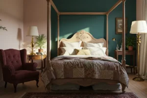 Chambre à coucher élégante avec un lit à baldaquin en bois clair, des coussins blancs et un dessus de lit patchwork, accompagnée d'un fauteuil bordeaux et de lampes dorées.